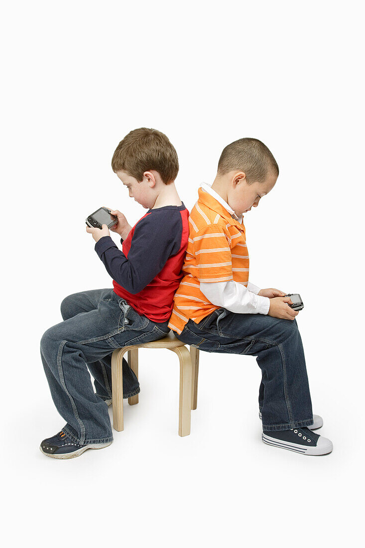 Boys with Handheld Video Games Sitting Back to Back