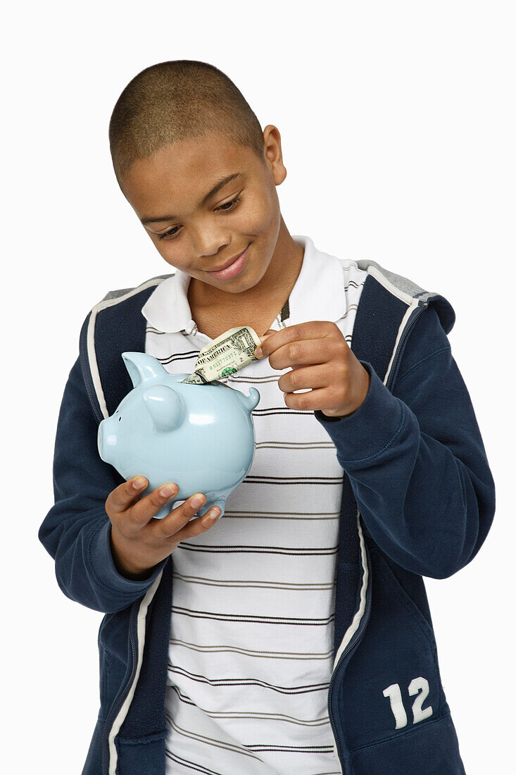 Boy Putting Money in Piggy Bank