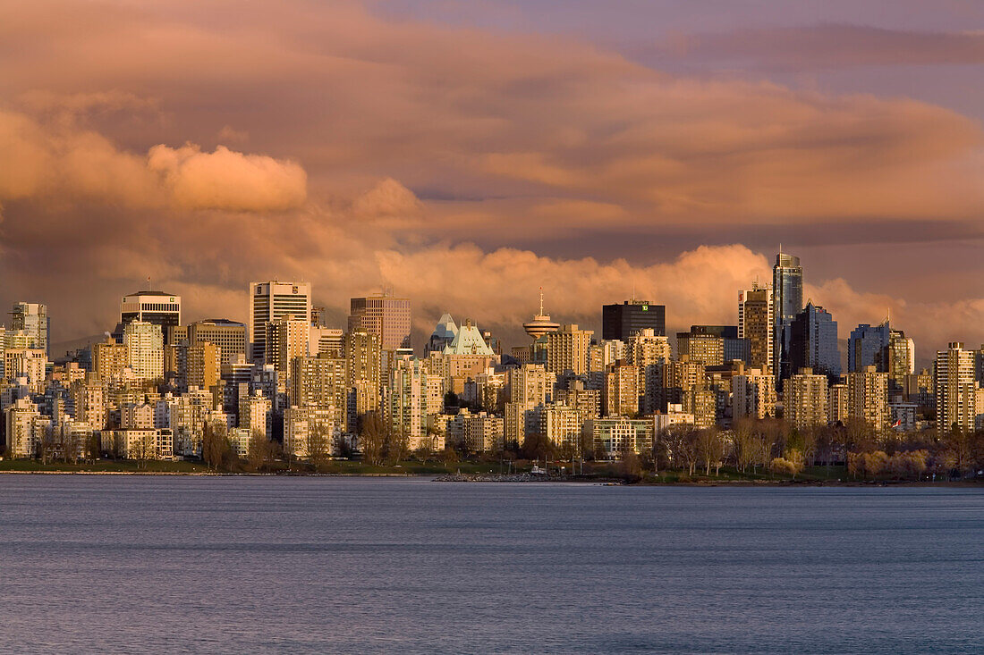 Stadtbild und Uferpromenade von Vancouver, Kanada, in der Dämmerung, mit warmem Licht über den Gebäuden unter einem bewölkten Himmel, Vancouver, British Columbia, Kanada