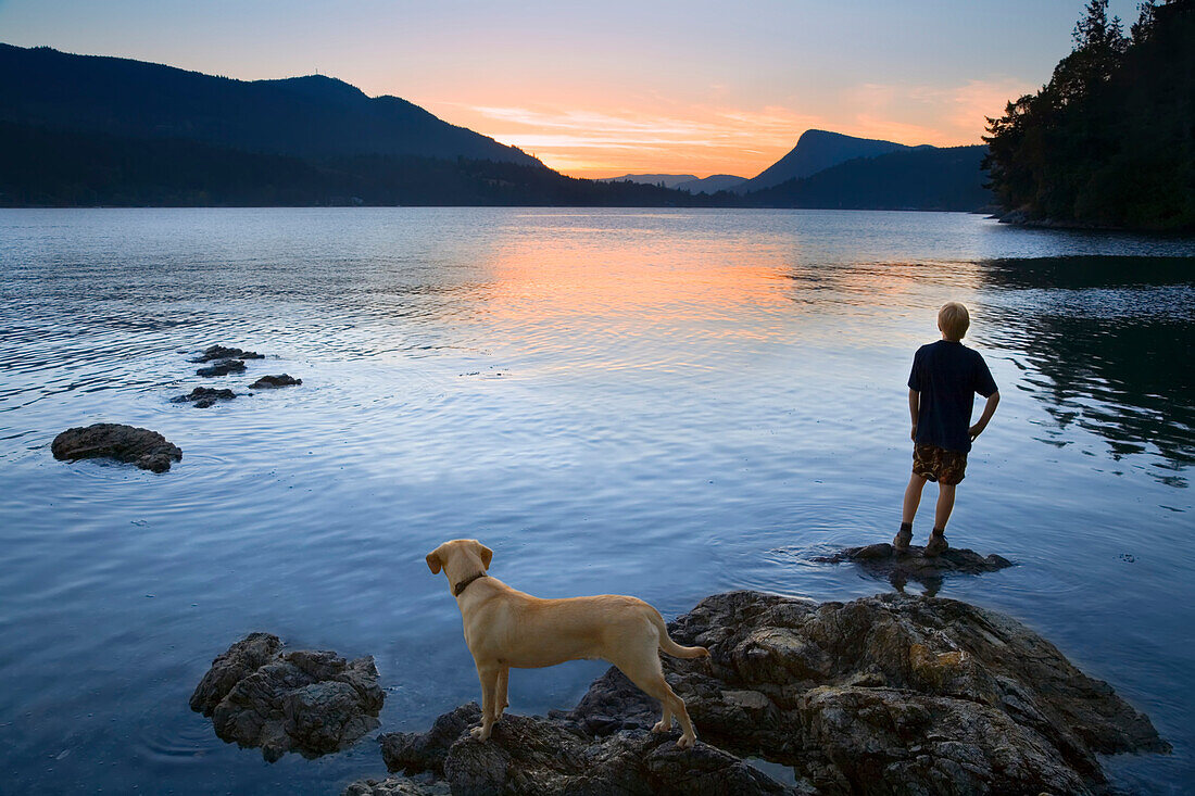 Teenager und Hund bei Sonnenuntergang, Fulford Harbour, Salt Spring Island, British Columbia, Kanada