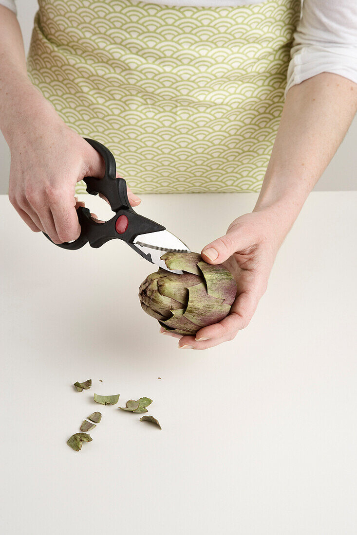 Frau bereitet Artischocke zum Kochen vor