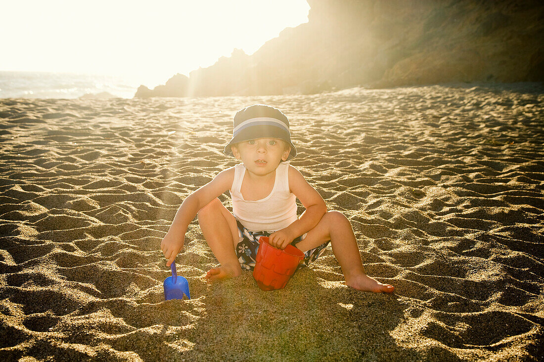 Porträt eines Jungen beim Graben im Sand am Strand
