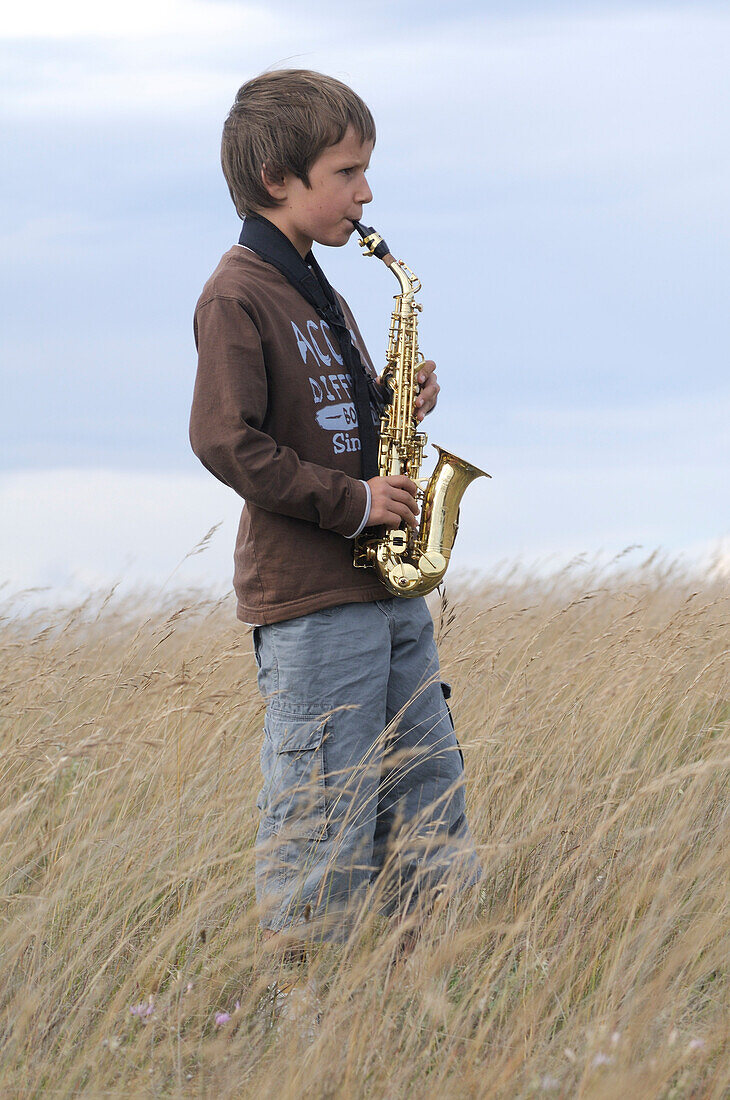 Junge spielt Saxophon auf einem Feld