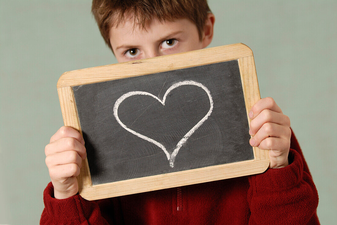 Junge hält Kreidetafel mit gezeichnetem Herz