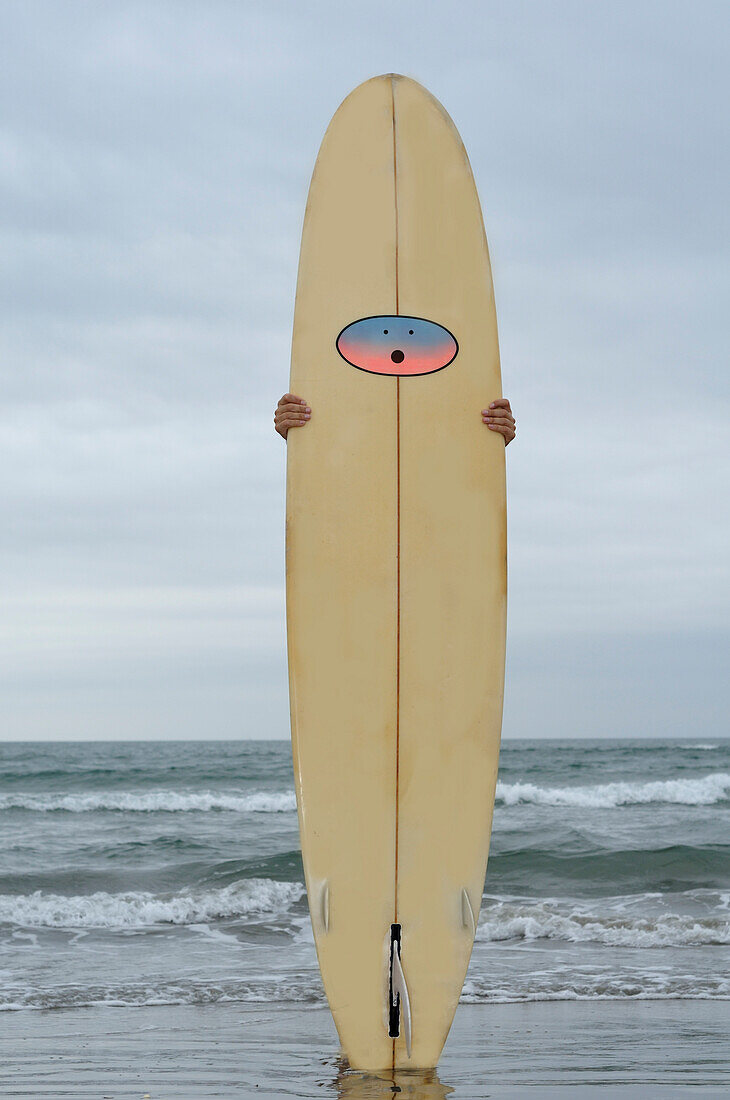 Mann hält Surfbrett am Strand