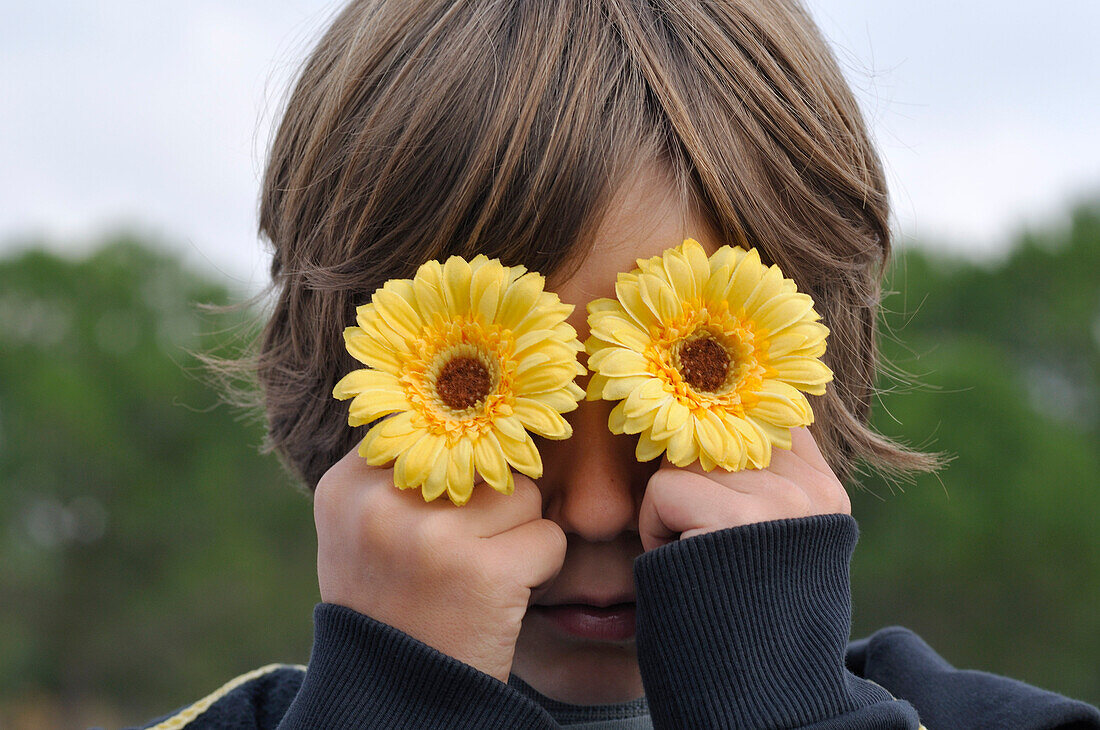 Boy Holding Flowers over Eyes