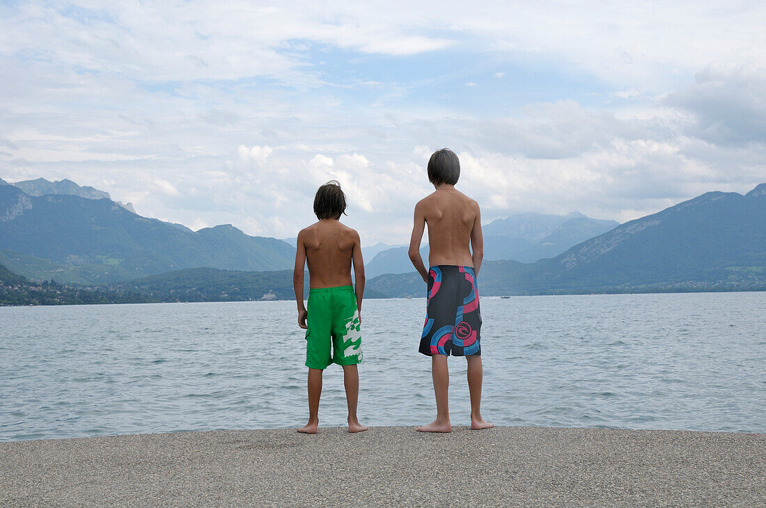 Rückenansicht eines Jungen am Ufer eines Sees, Annecy, Alpen, Frankreich