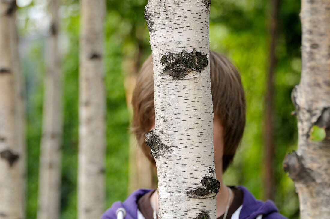 Boy Hidden Behind Tree trunk