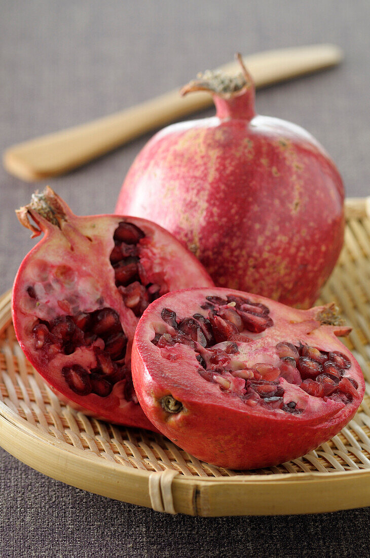 Close-up of Pomegranates on Tray,One cut in half on Grey Background,Studio Shot