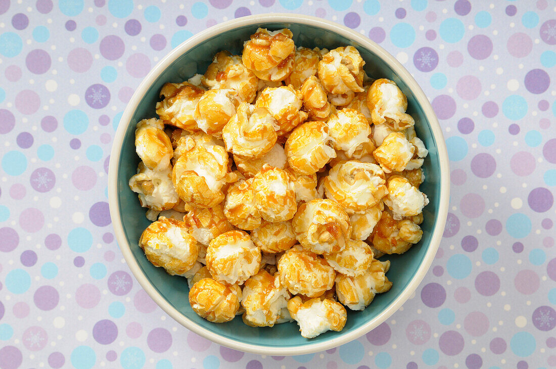 Overhead View of Caramel Popcorn in Bowl on Purple Polka Dot Background,Studio Shot