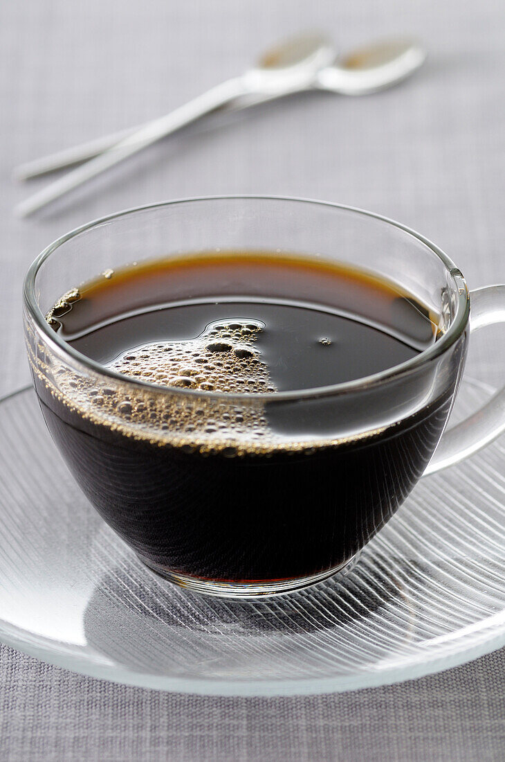 Close-up of Black Coffee in Glass Cup and Saucer on Grey Background,Studio Shot