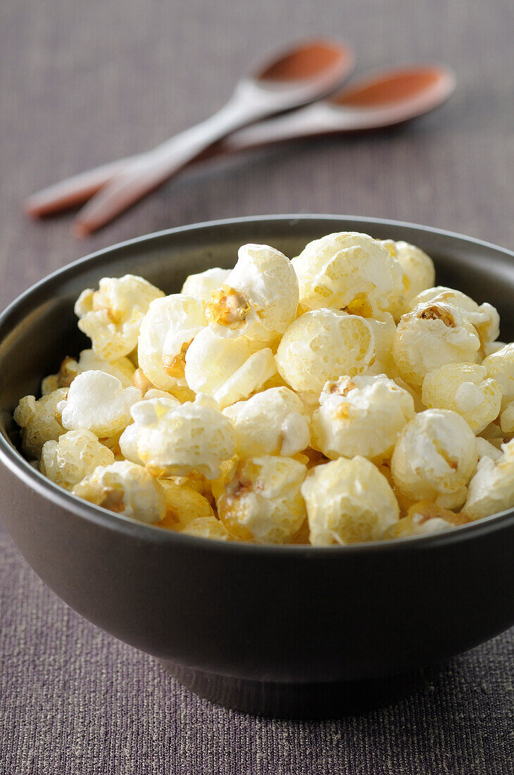 Close-up of Bowl of Popcorn with Wooden Spoons in Background,Studio Shot