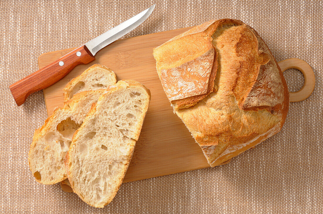 Draufsicht auf Brot auf Schneidebrett mit Messer