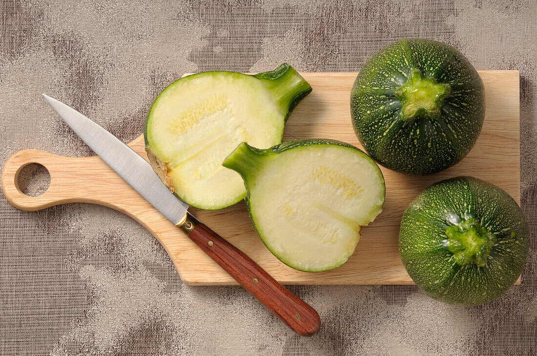 Overhead View of Round Zucchini on Cutting Board with Knife,One Cut in Half