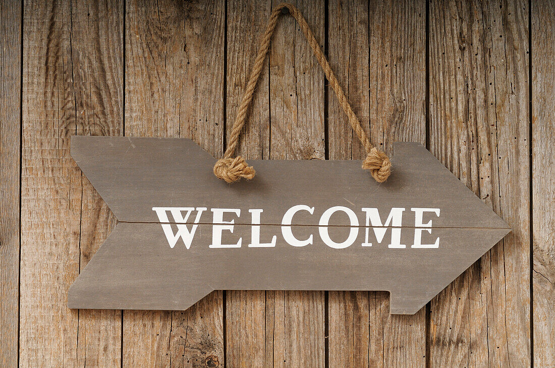 Welcome Sign shaped like Arrow Hanging on Wall