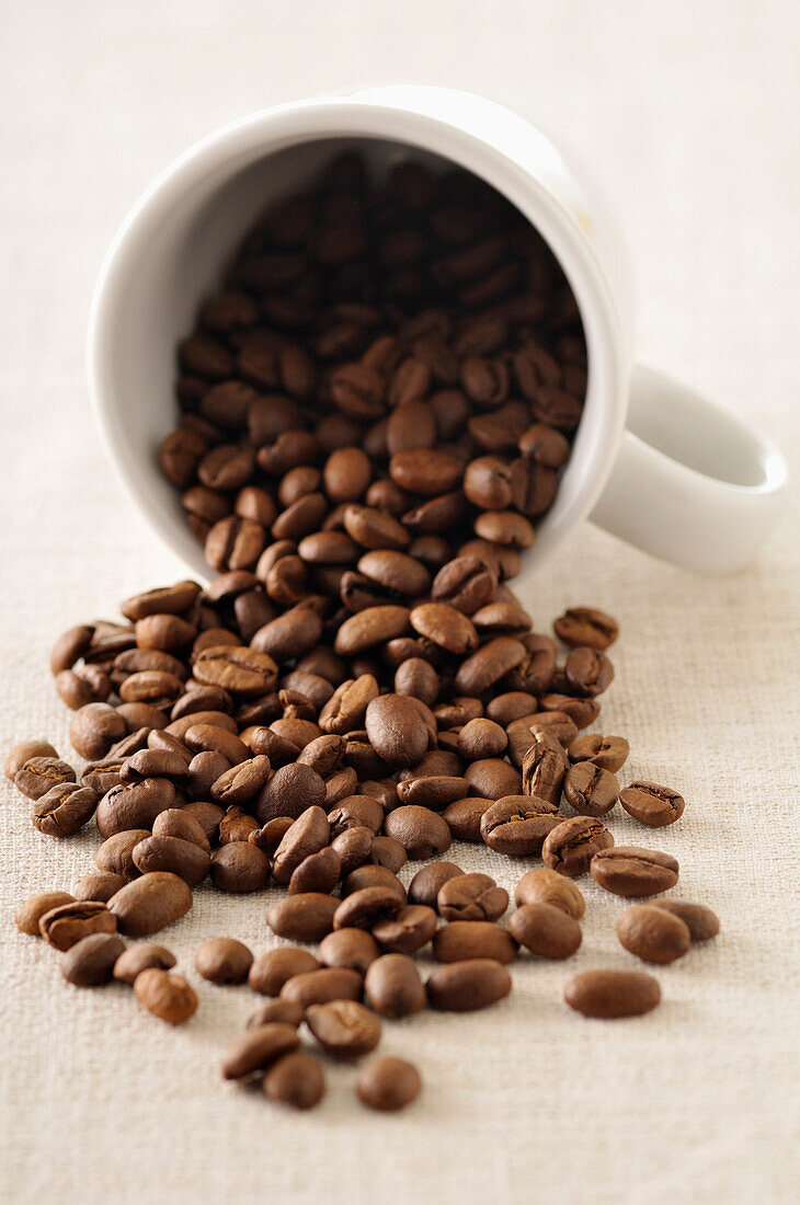 Nahaufnahme von Kaffeebohnen, die aus einer Tasse tropfen
