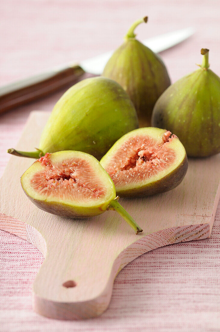 Close-up of Fresh Figs,One Cut in Half on Wooden Cutting Board on Pink Background