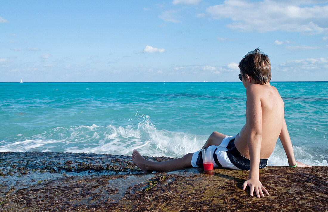 Junge sitzt in der Brandung, Playa del Carmen, Yucatan-Halbinsel, Mexiko