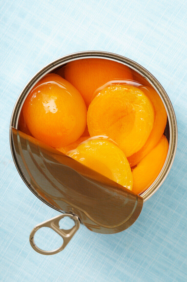 Open can of apricots,on blue background,studio shot