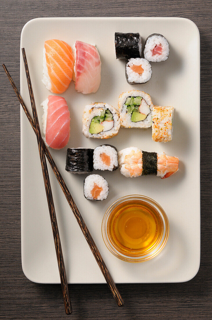 Draufsicht auf Sushi auf Teller mit Stäbchen, Studioaufnahme