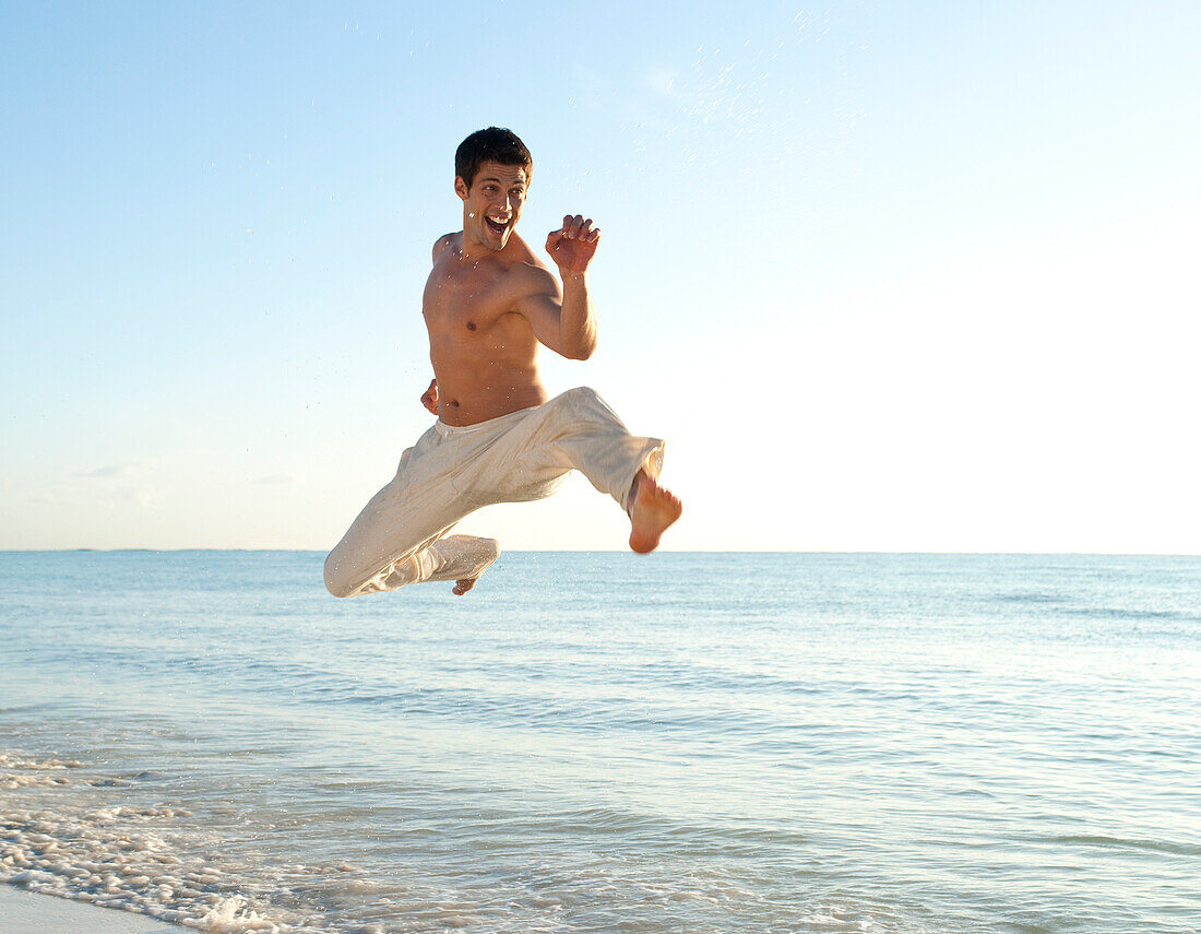 Mann springt am Strand in die Luft,REEF Playacar Resort und Spa,Playa del Carmen,Riviera Maya,Mexiko