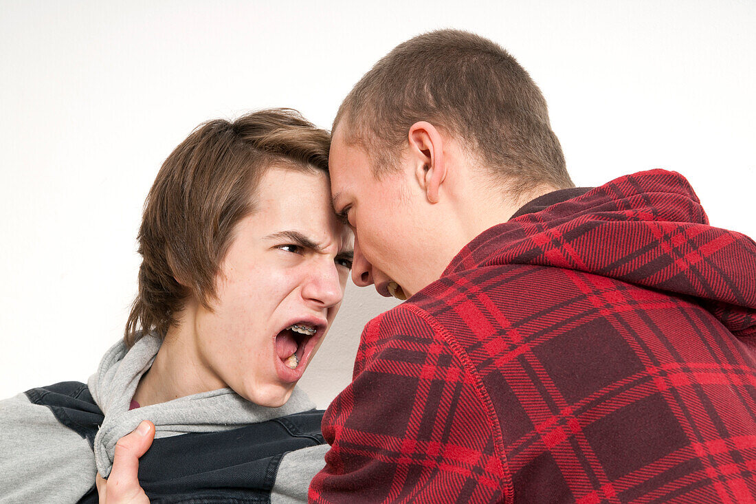 Großaufnahme von zwei Teenagern, die sich streiten und anschreien, Studioaufnahme auf weißem Hintergrund