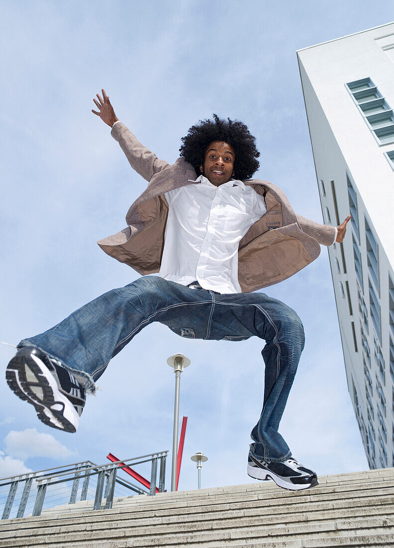 Portrait of young man outdoors,jumping down staircase,looking at camera and smiling,Mannheim,Germany