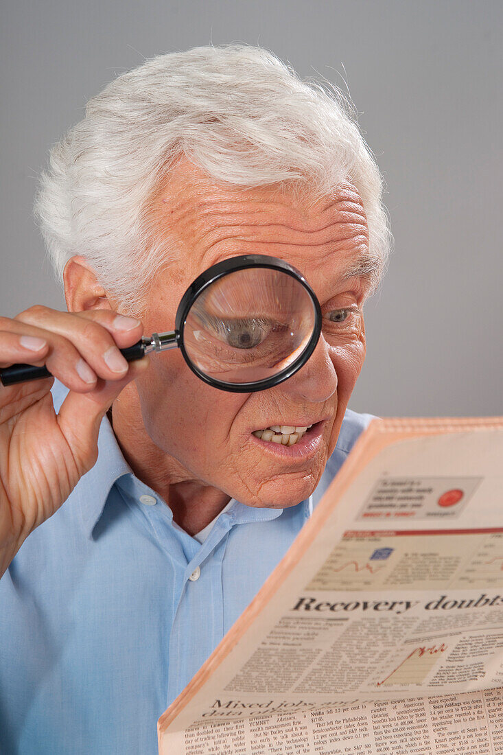 Man Looking at Newspaper with Magnifying Glass