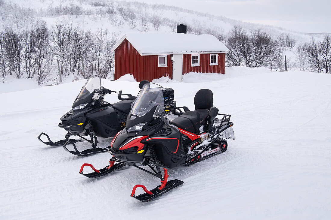 Schneemobile vor einer traditionellen samischen Hütte (Hytte) im Winter, in der Nähe des Sees Eoalbmejavri, Finnmark Plateau, Troms og Finnmark, Polarkreis, Norwegen, Skandinavien, Europa