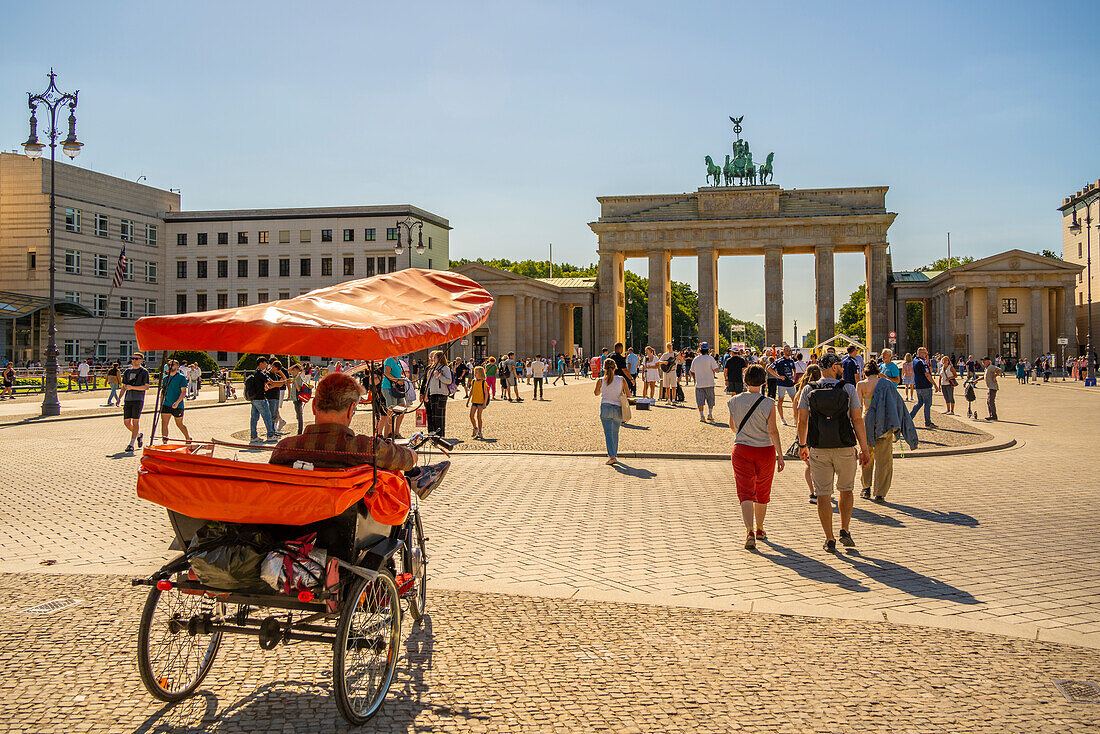 Blick auf das Brandenburger Tor, Rikscha und Besucher auf dem Pariser Platz an einem sonnigen Tag,Mitte,Berlin,Deutschland,Europa