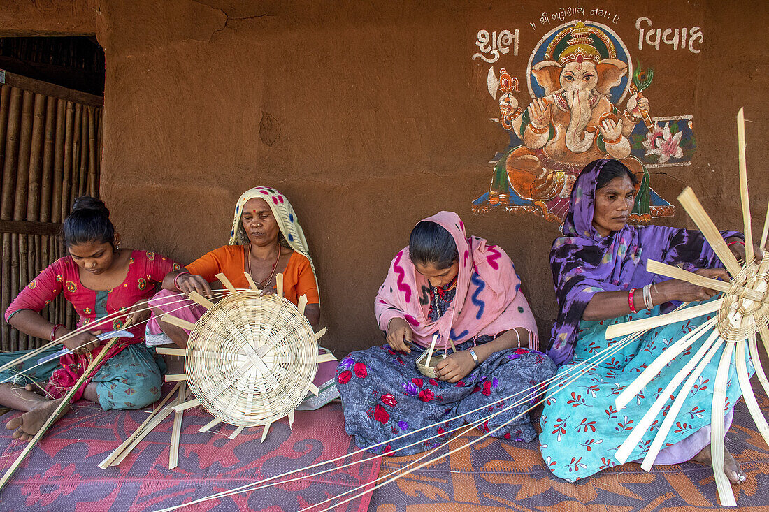 Adivasi-Frauen flechten Körbe in einem Dorf im Narmada-Distrikt, Gujarat, Indien, Asien