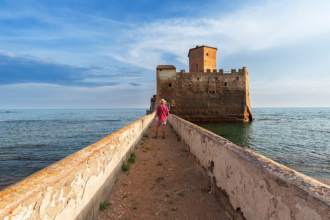 Tourist standing on top of the boardwalk admiring Torre Astura Castle,Nettuno municipality,province of Rome,Tyrrhenian sea,Latium (Lazio),Italy,Europe