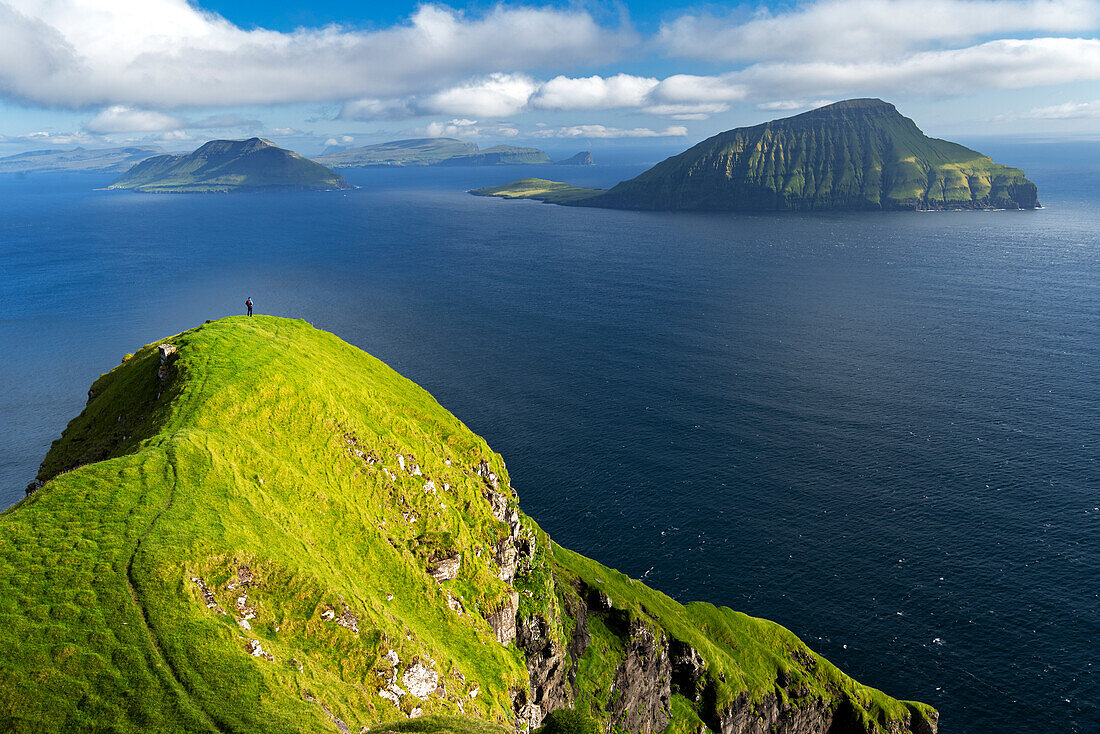 Wanderer wandert auf einer hohen Klippe mit Blick auf das Meer, Nordradalur, Streymoy Insel, Färöer Inseln, Dänemark, Europa