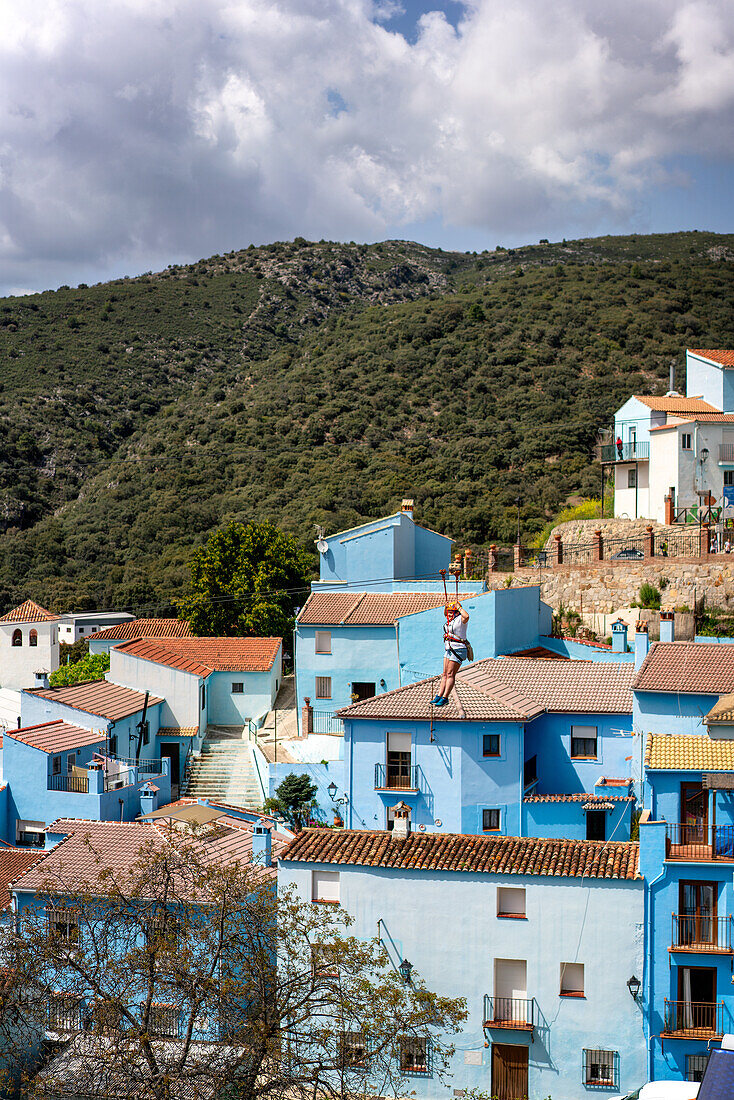 Person beim Rutschen (Seilrutsche) im blau gestrichenen Schlumpfdorf von Juzcar, Region Pueblos Blancos, Andalusien, Spanien, Europa