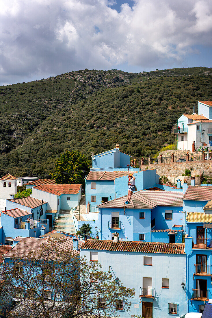 Person doing slide (zip line) in blue painted Smurf village of Juzcar,Pueblos Blancos region,Andalusia,Spain,Europe