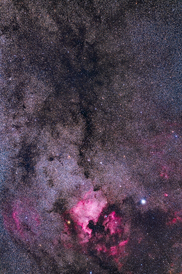 This frames the region of northern Cygnus containing the bright emission nebulas,the North America and Pelican Nebulas,at bottom,and the dark nebula called LeGentil 3 or the Funnel Cloud Nebula at top,for its tornado-like shape. The latter is one of the darkest areas of the northern Milky Way,similar to the Coal Sack in the southern sky. The bright star at bottom right is Deneb. The small patch of emission nebulosity to the right of Deneb is Sharpless 2-112. Above it is Sh2-115. The large nebula at bottom left is the Clamshell Nebula or Sharpless 2-119. The curving nebula below the Pelican Neb
