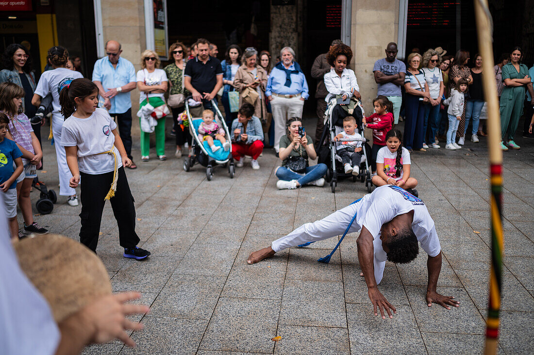 Mitglieder der Mestre Branco Capoeira Escola demonstrieren auf der Straße während der Fiestas de El Pilar in Zaragoza, Aragonien, Spanien