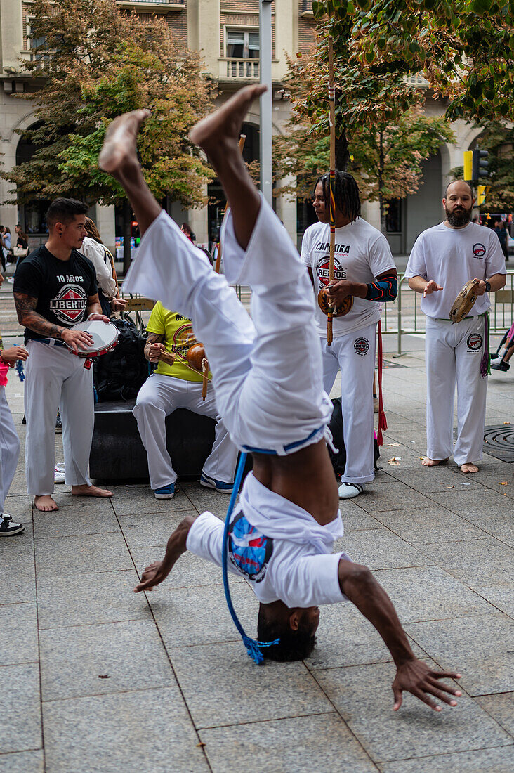 Mitglieder der Mestre Branco Capoeira Escola demonstrieren auf der Straße während der Fiestas von El Pilar in Zaragoza, Aragonien, Spanien