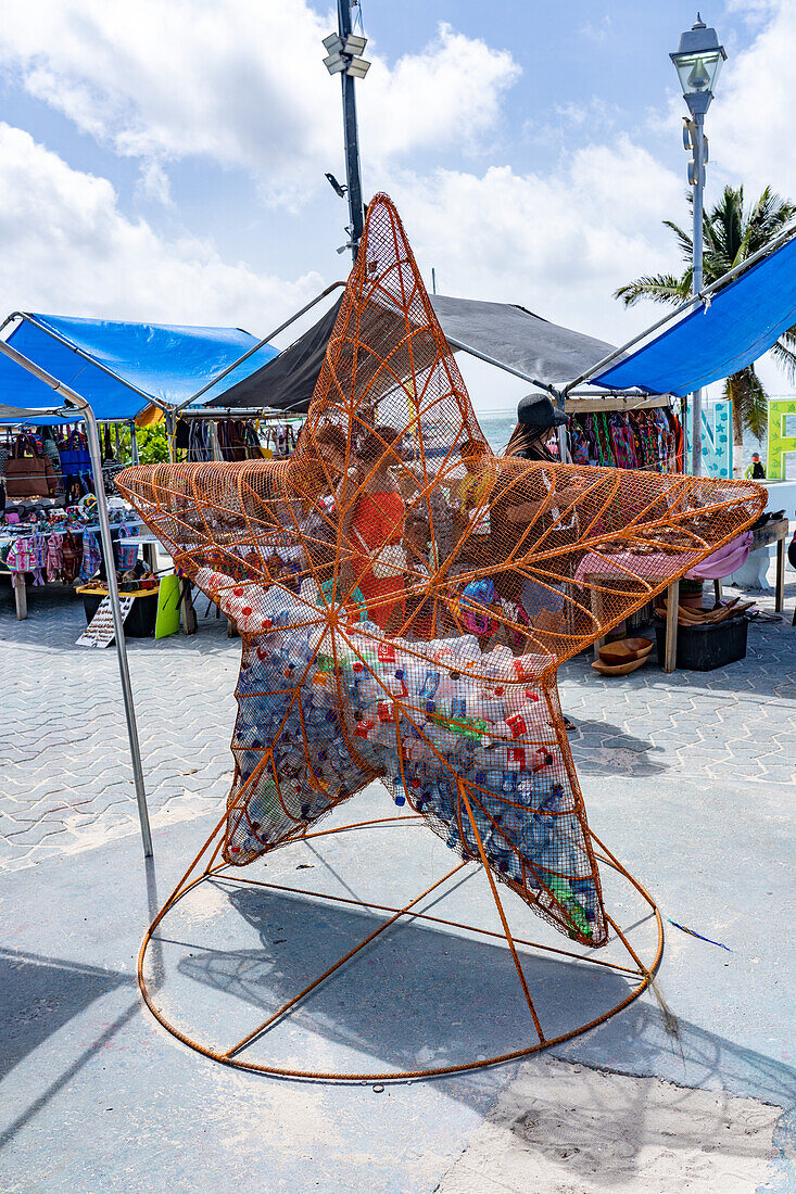 A metal bin in the shape of a starfish for recycling plastic water bottles in the open market in San Pedro,Ambergris Caye,Belize.