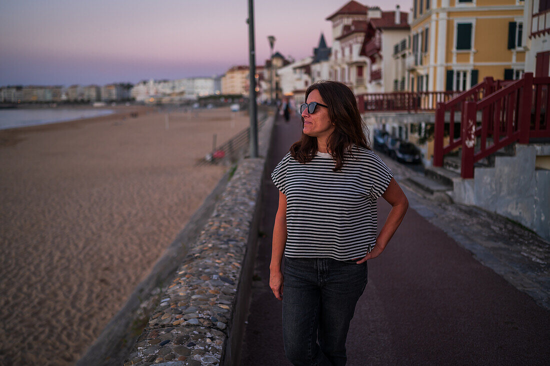 Frau mit Blick auf das Meer von der Promenade Jacques Thibaud vor dem Strand Grande Plage von Saint Jean de Luz, einem Fischerdorf an der Mündung des Flusses Nivelle im südwestfranzösischen Baskenland