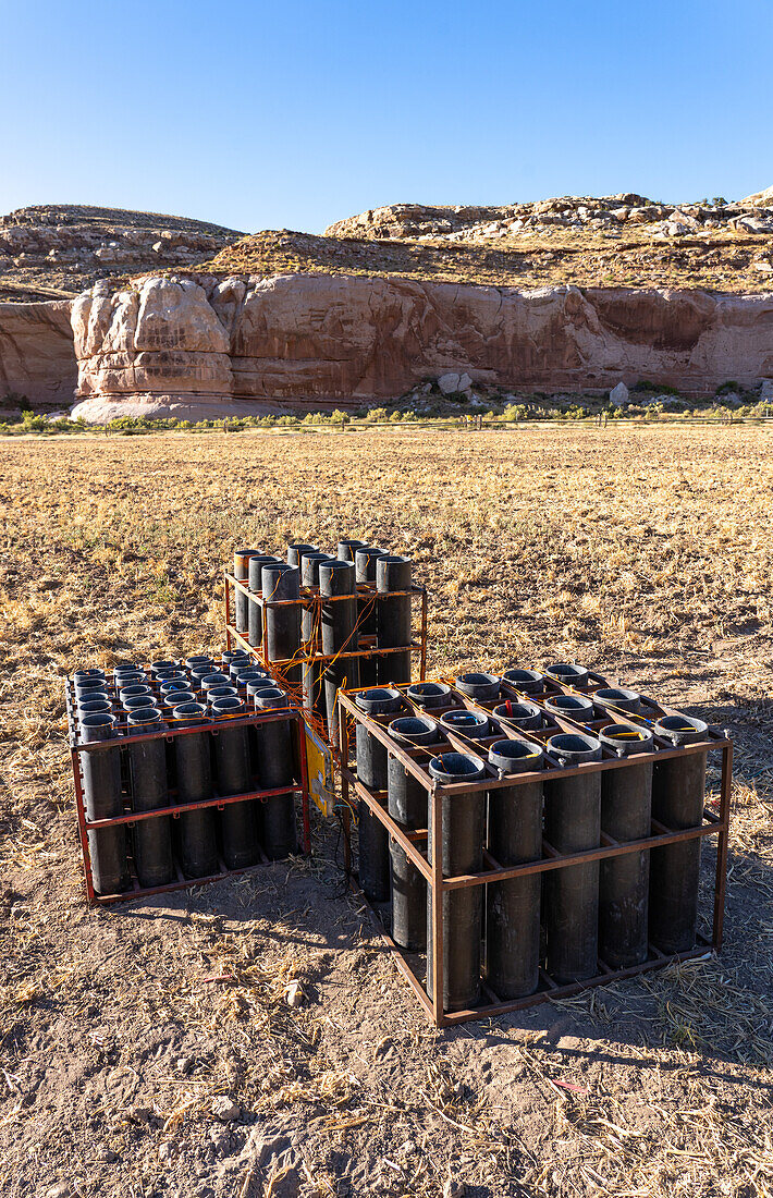 A battery of launchers for 4" & 6" pyrotechnic shells being prepared for a fireworks show in a field in Utah.