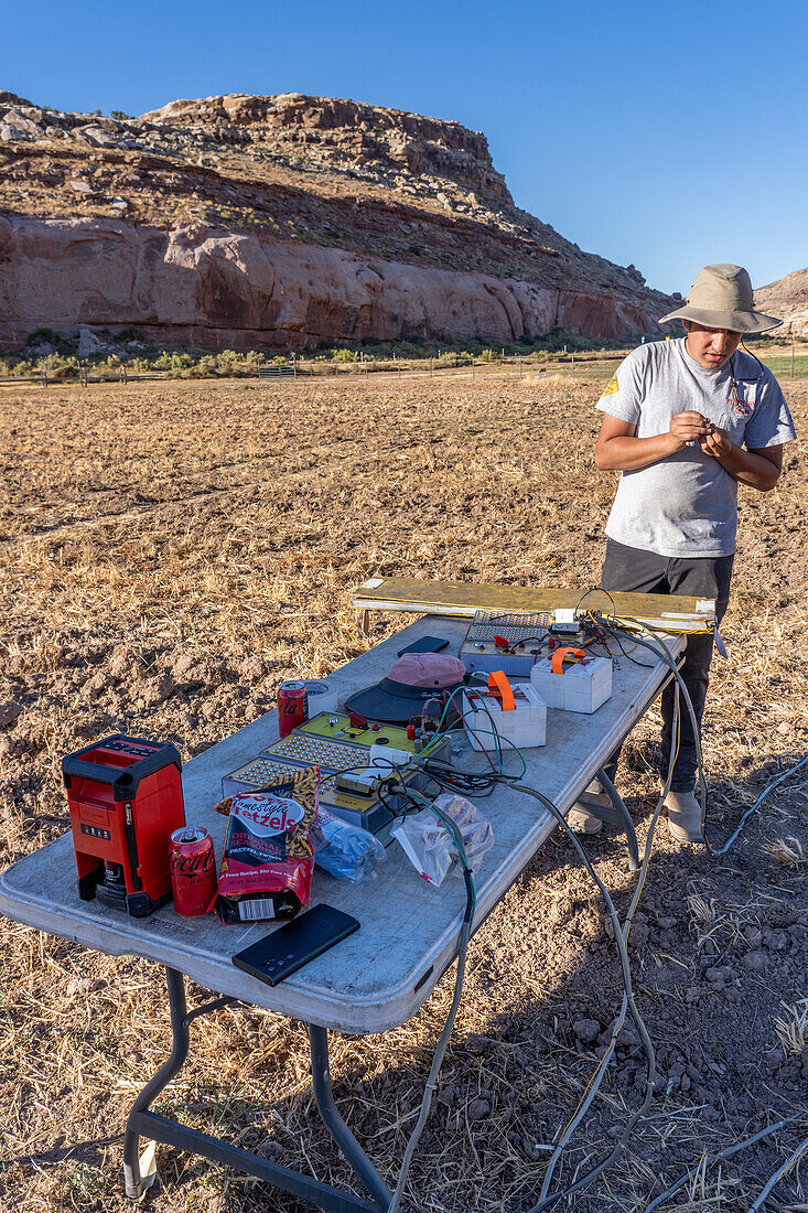 A technician sets up the controllers for fireworks launchers for a fireworks show in a field in Utah.