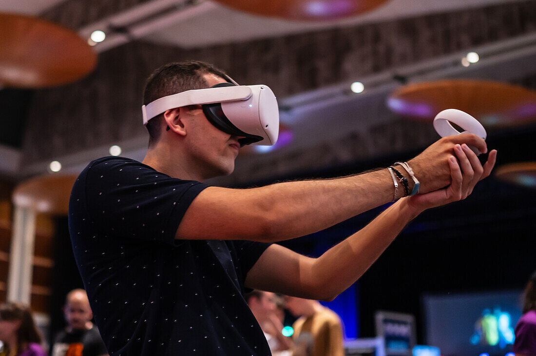 Junger Mann spielt mit dem Meta Quest 2 All-in-One VR-Headset während der ZGamer, einem Festival für Videospiele, digitale Unterhaltung, Brettspiele und YouTuber während der El Pilar Fiestas in Zaragoza, Aragonien, Spanien