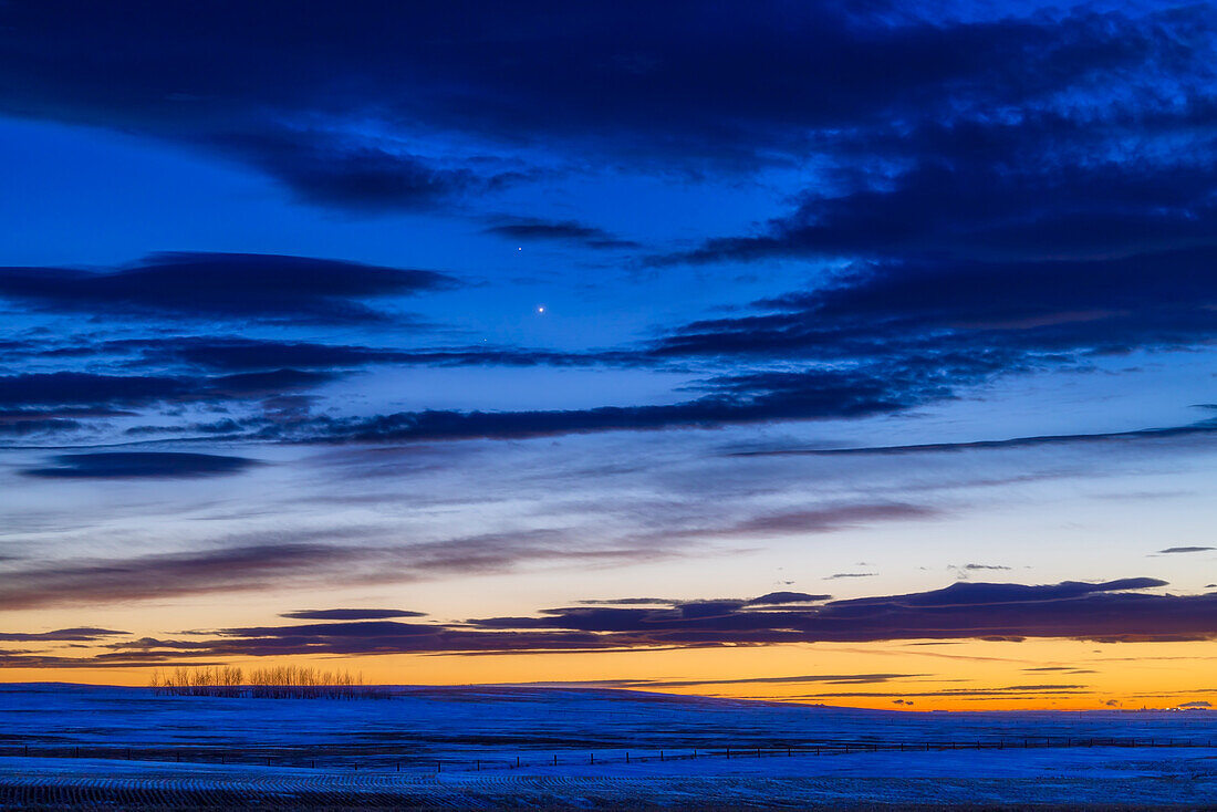 Venus unter dem dunkleren Saturn in der Abenddämmerung am 21. Januar 2023, dem Abend vor ihrer engen Konjunktion. Der Stern Deneb Algiedi, auch bekannt als Delta Capricorni, mit einer Helligkeit von 2,8 befindet sich unterhalb und links der Venus. Venus hatte eine Helligkeit von -3,9 und Saturn eine Helligkeit von 0,8.