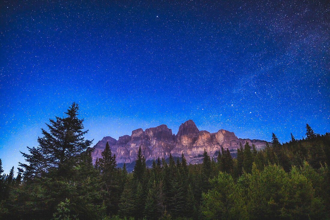 Die Sterne am nördlichen Himmel über dem Castle Mountain im Banff National Park, Alberta. Dies war am 6. Juni 2023 in einer sehr klaren Nacht, aber hell mit blauer Sommerdämmerung auf diesem Breitengrad von 51° N im Juni. Das W der Kassiopeia und die Milchstraße sind rechts zu sehen. Polaris ist oben.