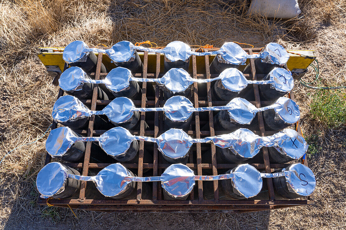 A battery of launchers for 4" pyrotechnic shells being prepared for a fireworks show in a field in Utah.