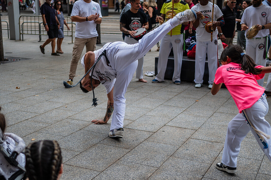 Mitglieder der Mestre Branco Capoeira Escola demonstrieren auf der Straße während der Fiestas von El Pilar in Zaragoza, Aragonien, Spanien