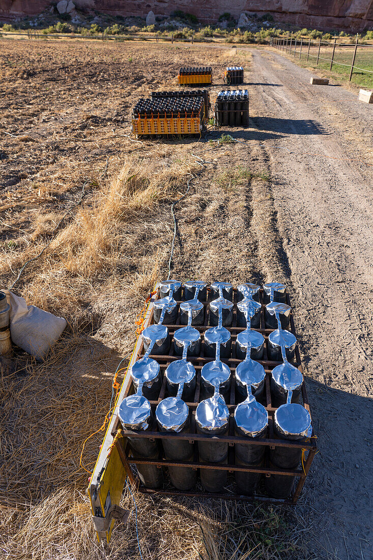 A battery of launchers for 4" pyrotechnic shells being prepared for a fireworks show in a field in Utah.
