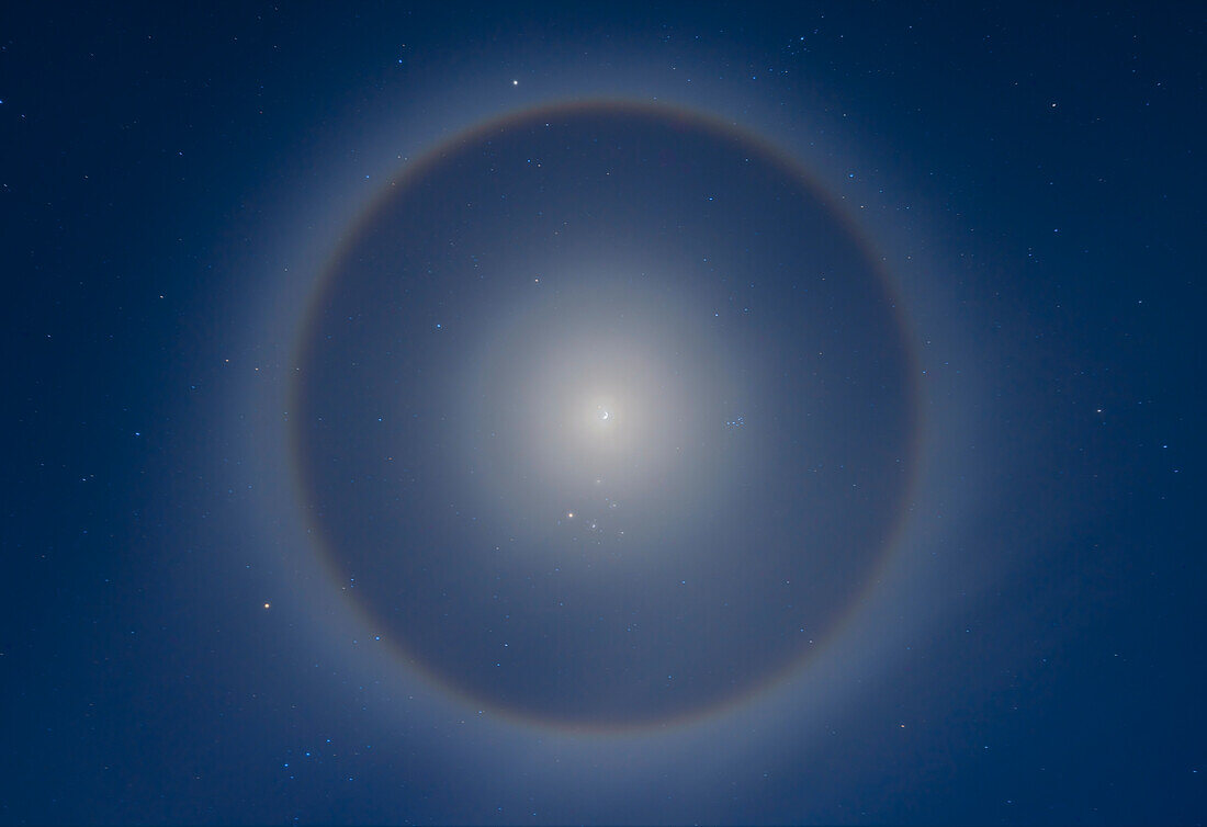 An ice crystal halo around the waxing gibbous Moon set in the winter stars of a January night. The 22° halo is most obvious and with a reddish and sharper inner rim.,and a bluish and more diffuse outer edge. But a faint inner 8° halo is also visible,a rare halo sometimes called the Van Buijsen Halo (according to Lynch and Livingston in their book Color and Light in Nature; Minnaert also mentions it in his seminal book The Nature of Color and Light in the Open Air). It is not a lens flare as shots taken with the Moon well off to one side of the frame still show the inner halo centred on the Moo