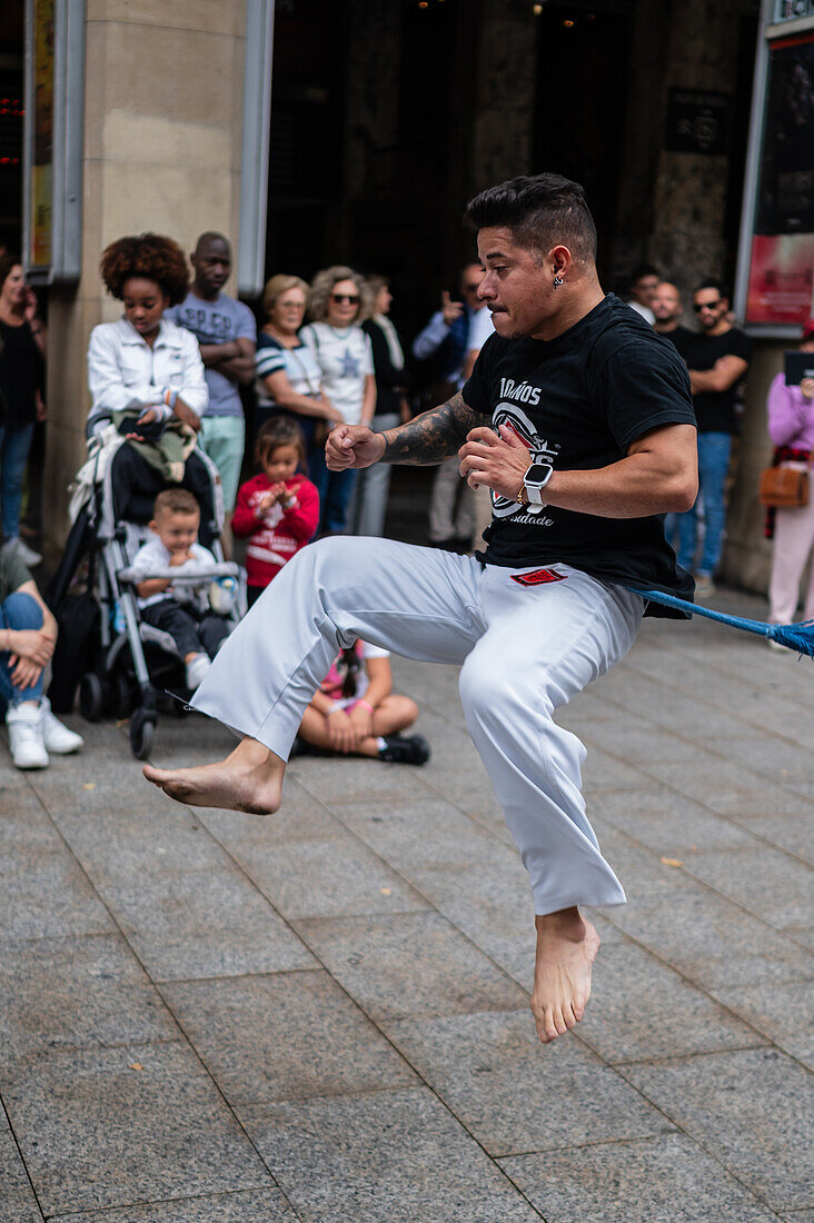 Mitglieder der Mestre Branco Capoeira Escola demonstrieren auf der Straße während der Fiestas de El Pilar in Zaragoza, Aragonien, Spanien